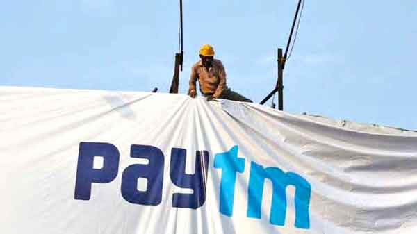 Man putting a large banner of paytm on a wall